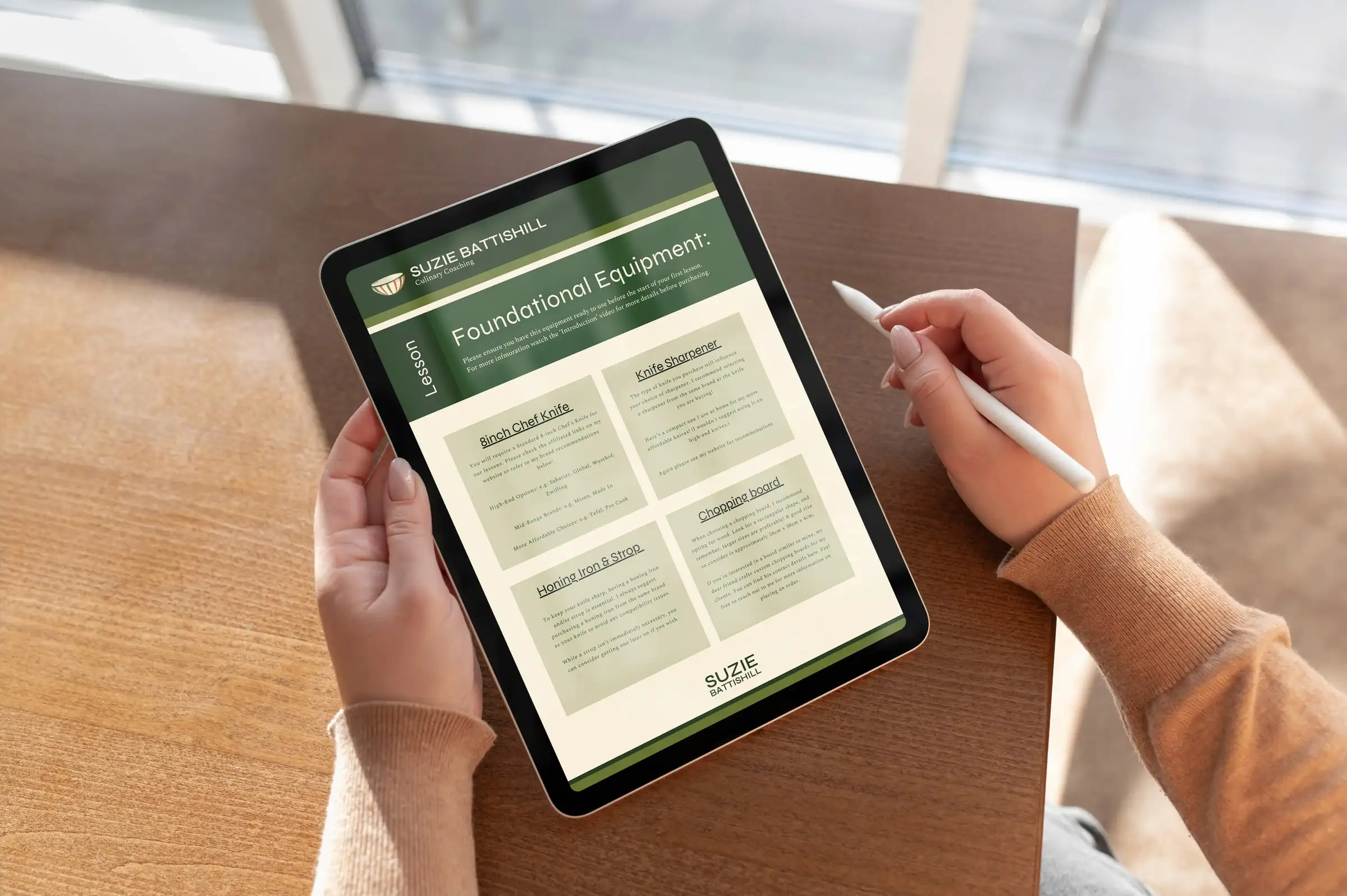 A tablet showing a Suzie Battishill lesson handout on foundational kitchen equipment, under a green branded header